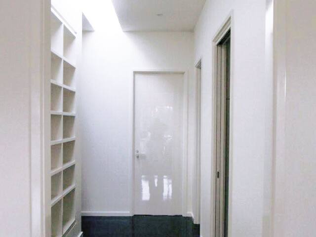 Hallway and built-in shelving. Smooth white walls and joinery in a bright hallway.