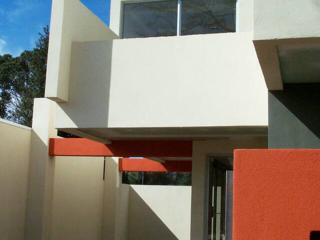 Rendered townhouse with feature colour. Crisp white render with an accent wall.