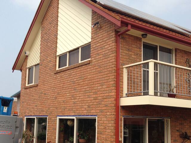 A double-storey brick home with freshly painted trims, balcony and window frames