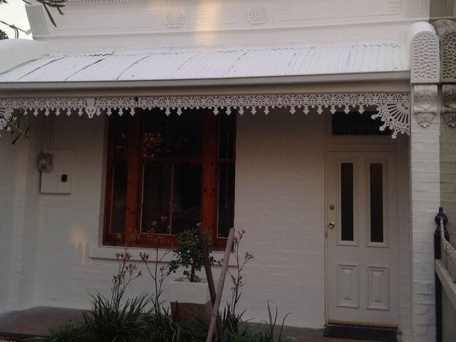 The front of a Victorian cottage with a painted verandah, front door and window trims