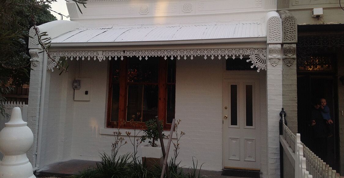 The front of a Victorian cottage with a painted verandah, front door and window trims